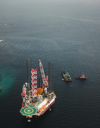 Aerial view of an offshore oil platform with support vessels in the open sea, showcasing industrial maritime infrastructure.